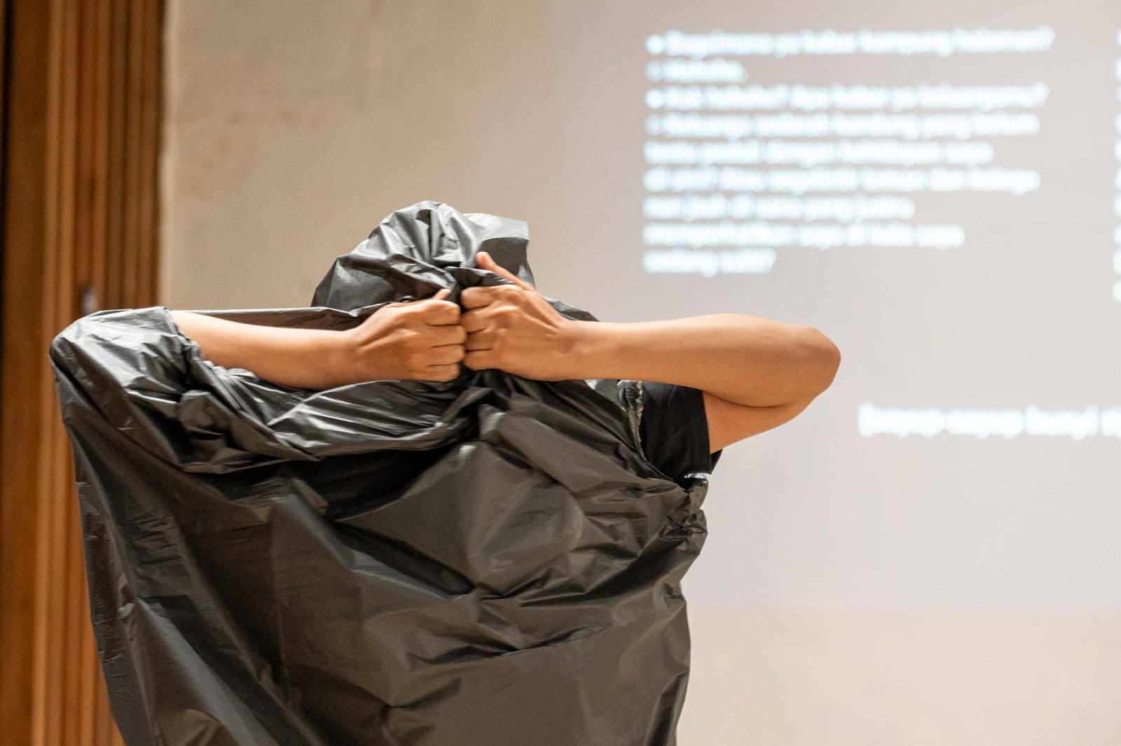 Siska melesapkan tubuhnya ke dalam plastik trash bag hitam, ia bergerak menggeliat serupa menyimpan ledakan emosional yang tertahan—sembari melubangi plastik dan memunculkan mata yang mengintip, tangan yang ingin meraih hal-hal yang sulit diraih.