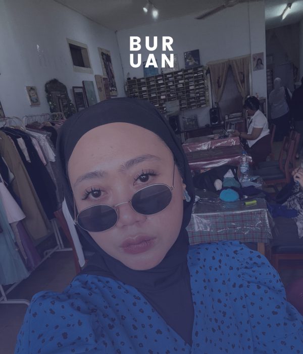 Aya Cannina, penyair perempuan asal Bekasi, menggunakan baju volkadot berwarna biru dan menggunakan kaca hitam dengan jilbab hitam.