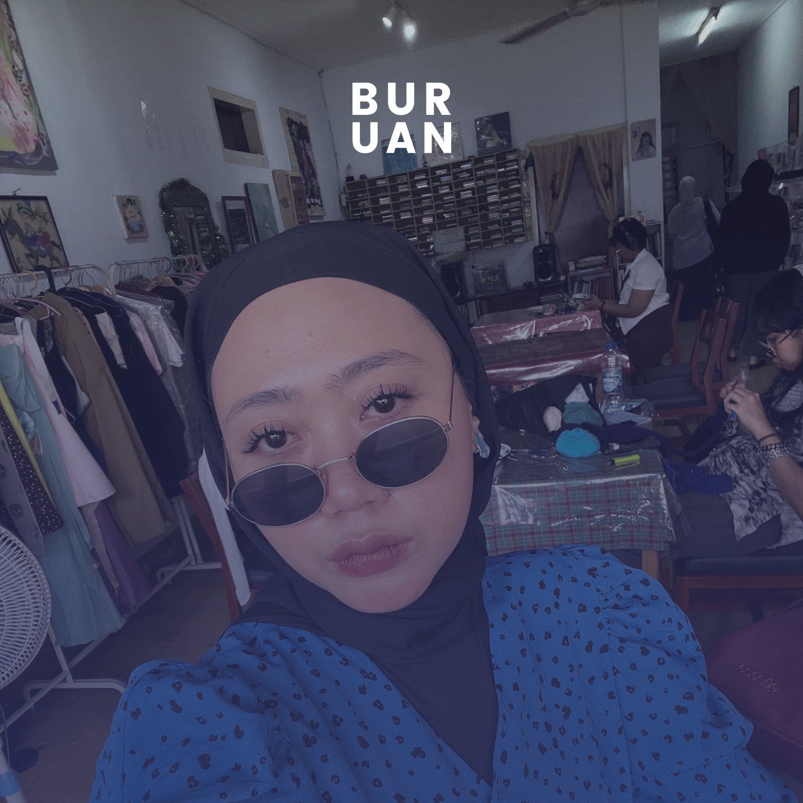 Aya Cannina, penyair perempuan asal Bekasi, menggunakan baju volkadot berwarna biru dan menggunakan kaca hitam dengan jilbab hitam.