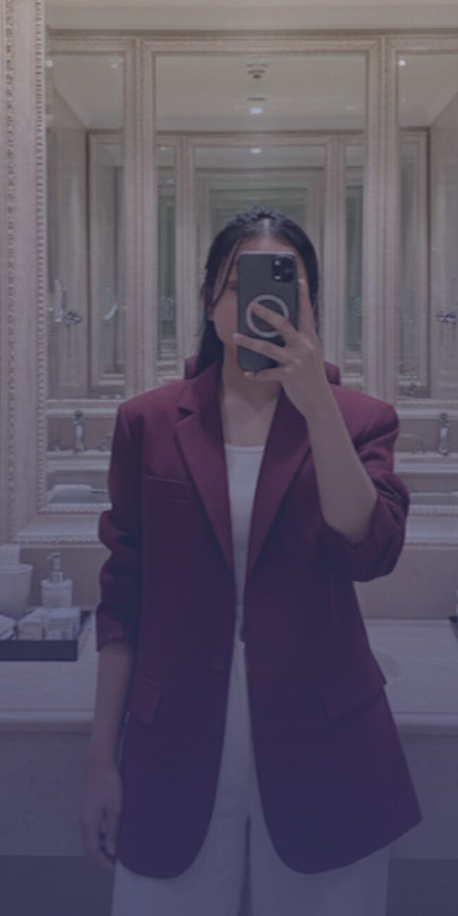 Cerpenis Buruan.co, Erniati Efendi, berfose di depan cermin menggunakan blazer merah.