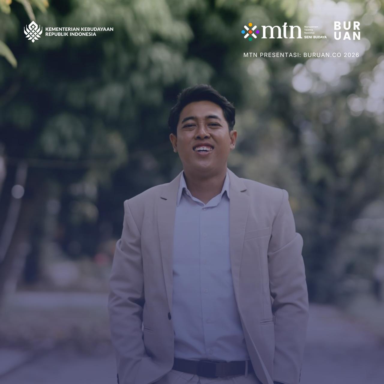 Alfa Zain mengenakan jas krem dan kemeja putih berpose dan tersenyum. Foto setengah badan.